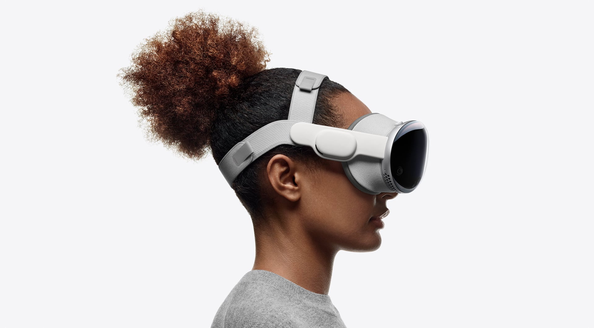 Frau trägt das Vision Pro-Headset von Apple mit Dual-Loop-Band vor einem grauen Hintergrund