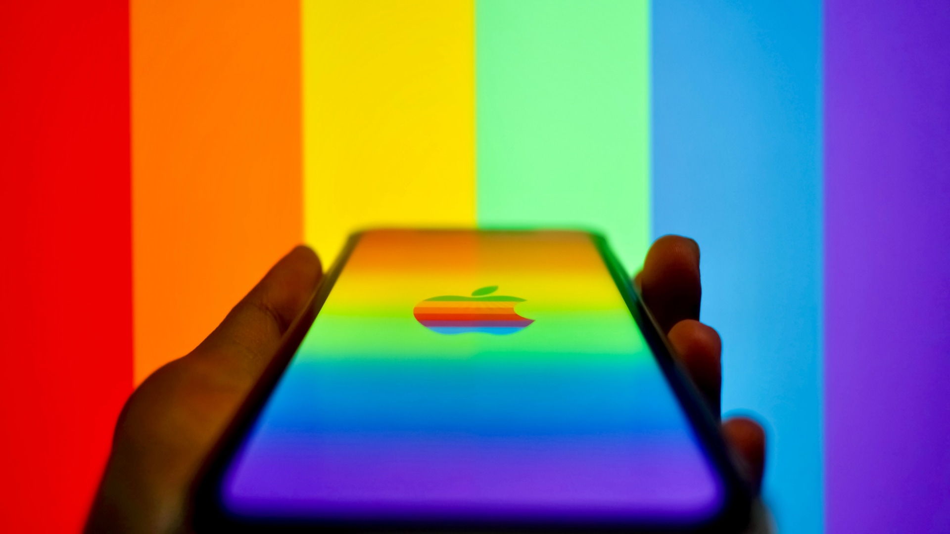 Und wenn ich das iPhone in der Hand halte, wird auf dem Bildschirm ein Apple-Logo in Regenbogenfarben angezeigt, im Hintergrund sind Regenbogenstreifen zu sehen