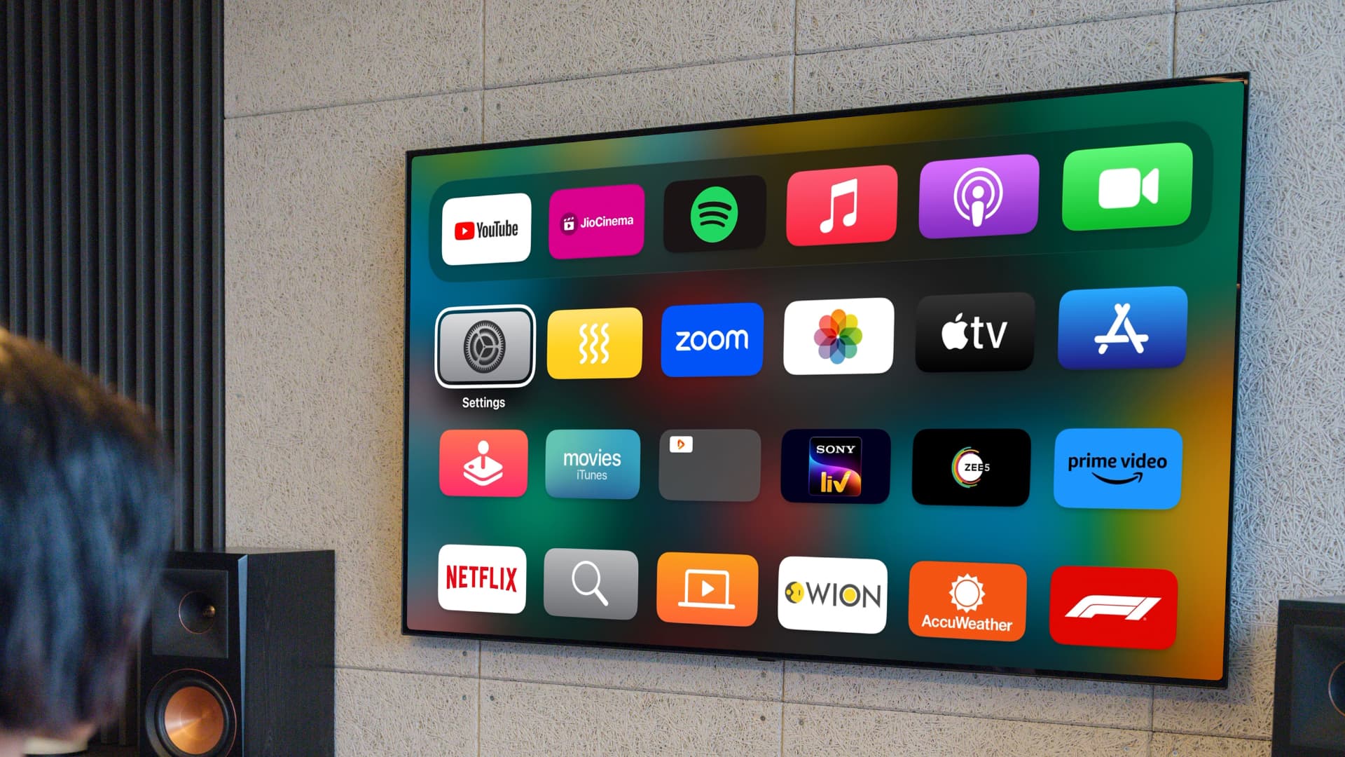 Fernseher an der Wand, auf dem Apple TV-Apps auf dem Startbildschirm angezeigt werden