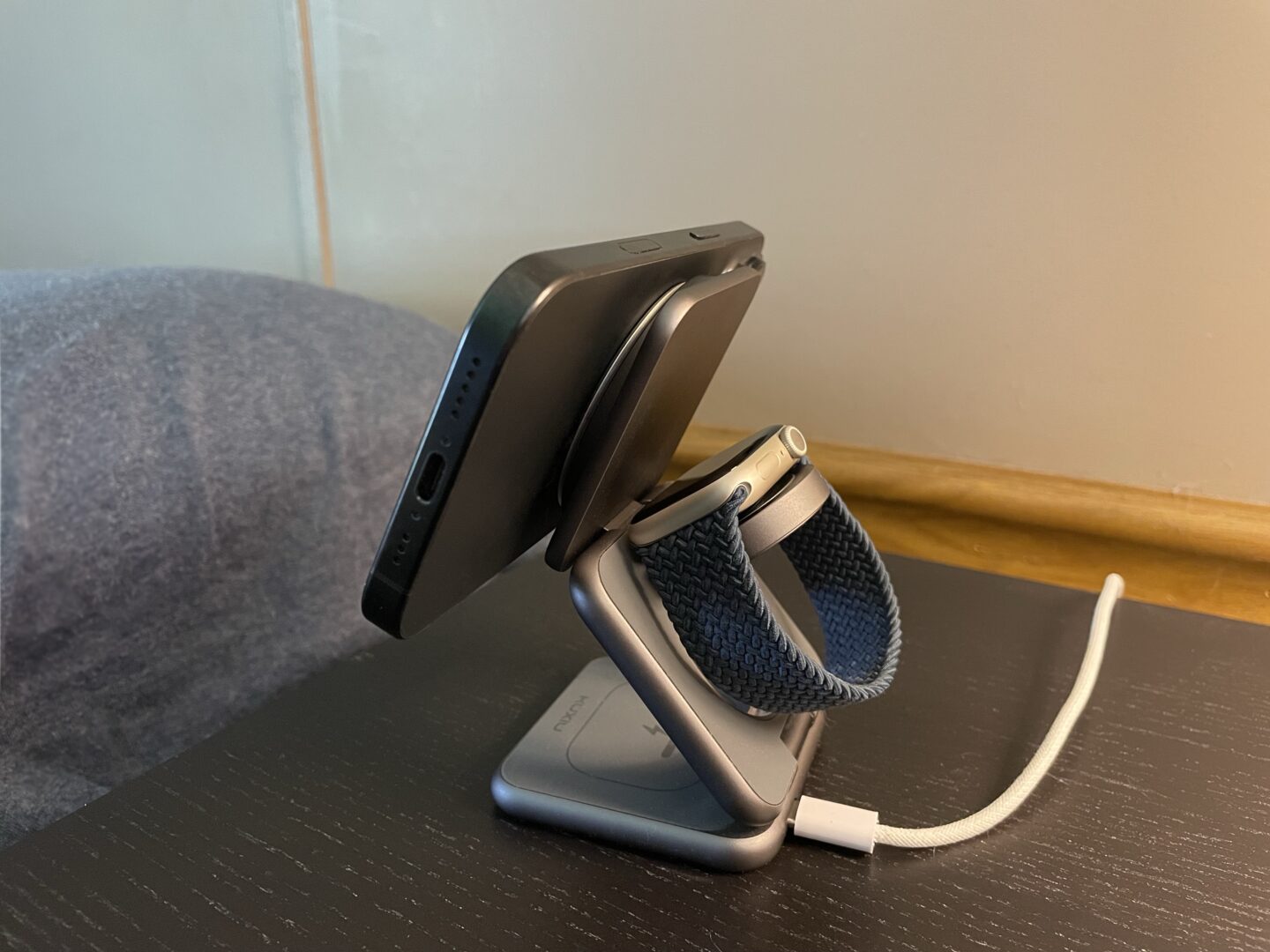 Snap Grip Luxe Magsafe Foto eines schwarzen iPhone 16 -Profi, das auf einem Nachttisch an einem Magsafe -Ladegerät mit dem OHSNAP Snap 4 Luxe sitzt.